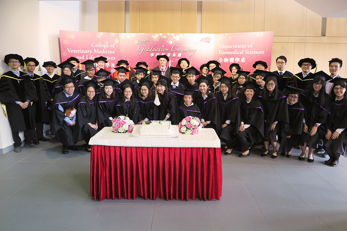 Group photo of graduates with graduation cake.