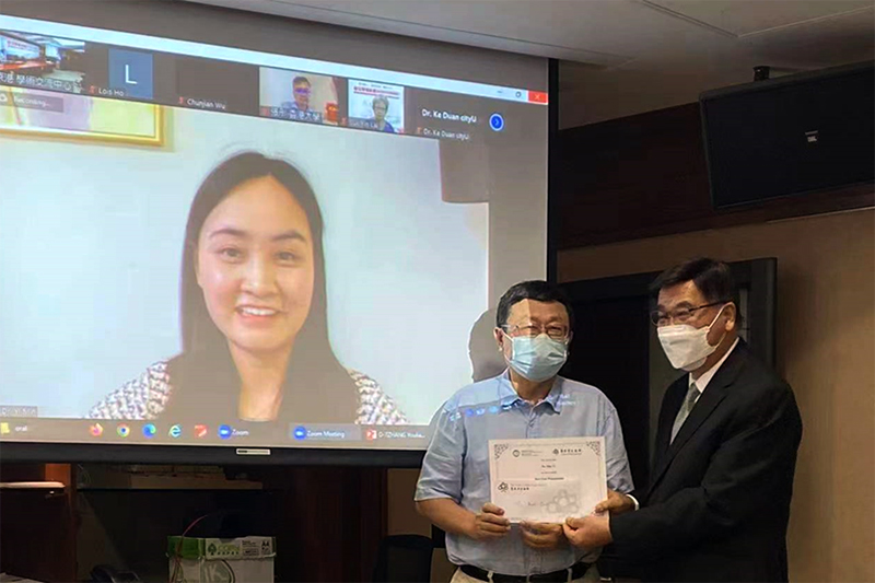 Professor Yu Huang, supervisor of Dr Min Yi, received the Best Oral Presentation Award on behalf of Dr Min Yi (on screen) from Professor Yuk-shan Wong (right), Chairman of the Academic Committee of the Hong Kong Scholars Program.