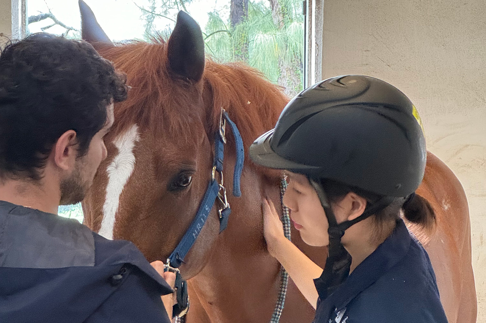 Yoolim (right) learns how to put a bridle on a horse.