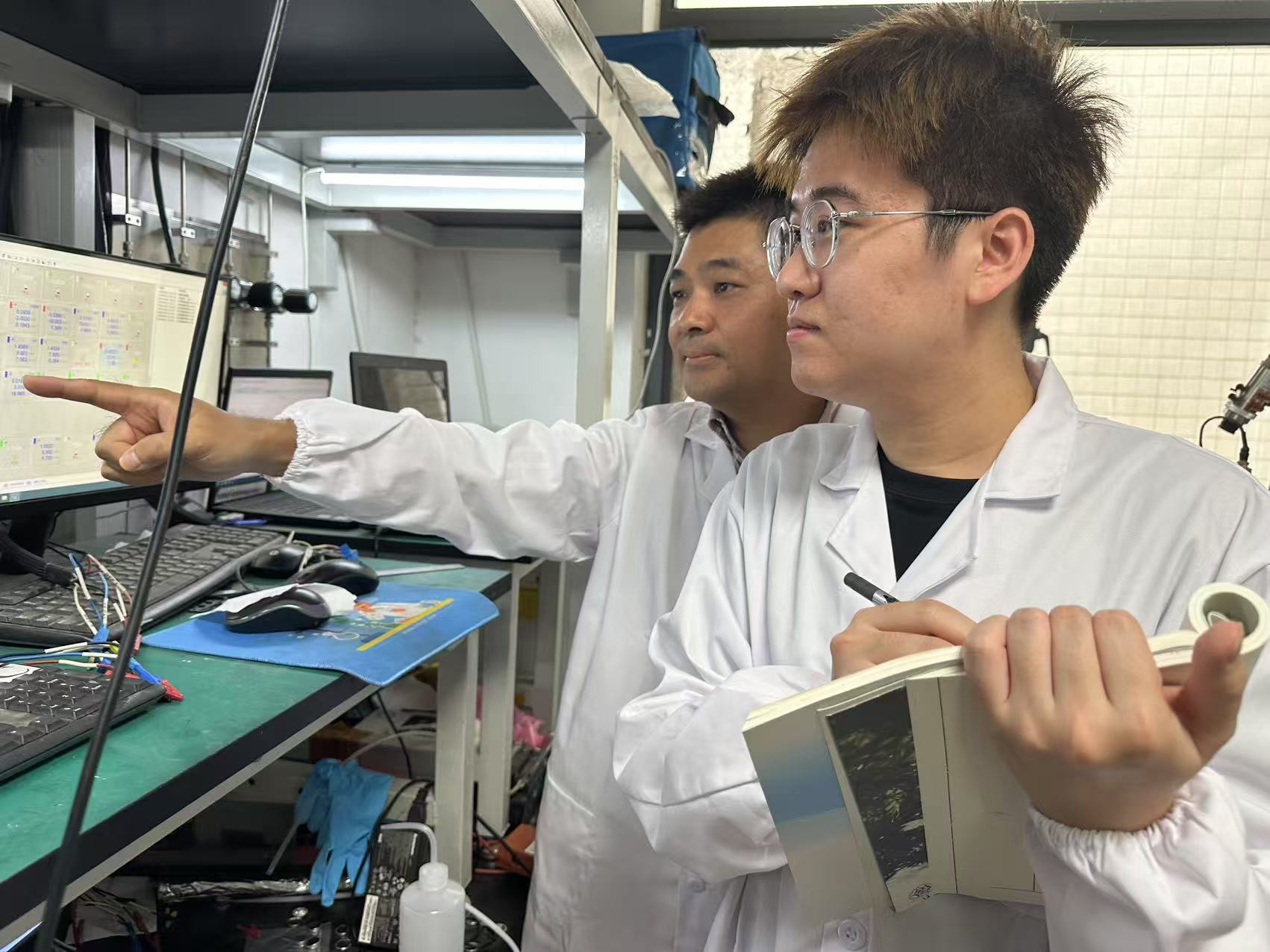 Professor Liu Bin (left) demonstrates the innovative cathode technology for stable water electrolysis to a colleague in the lab.