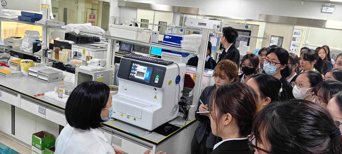 Students observe a demonstration of advanced laboratory equipment during the hospital visit.