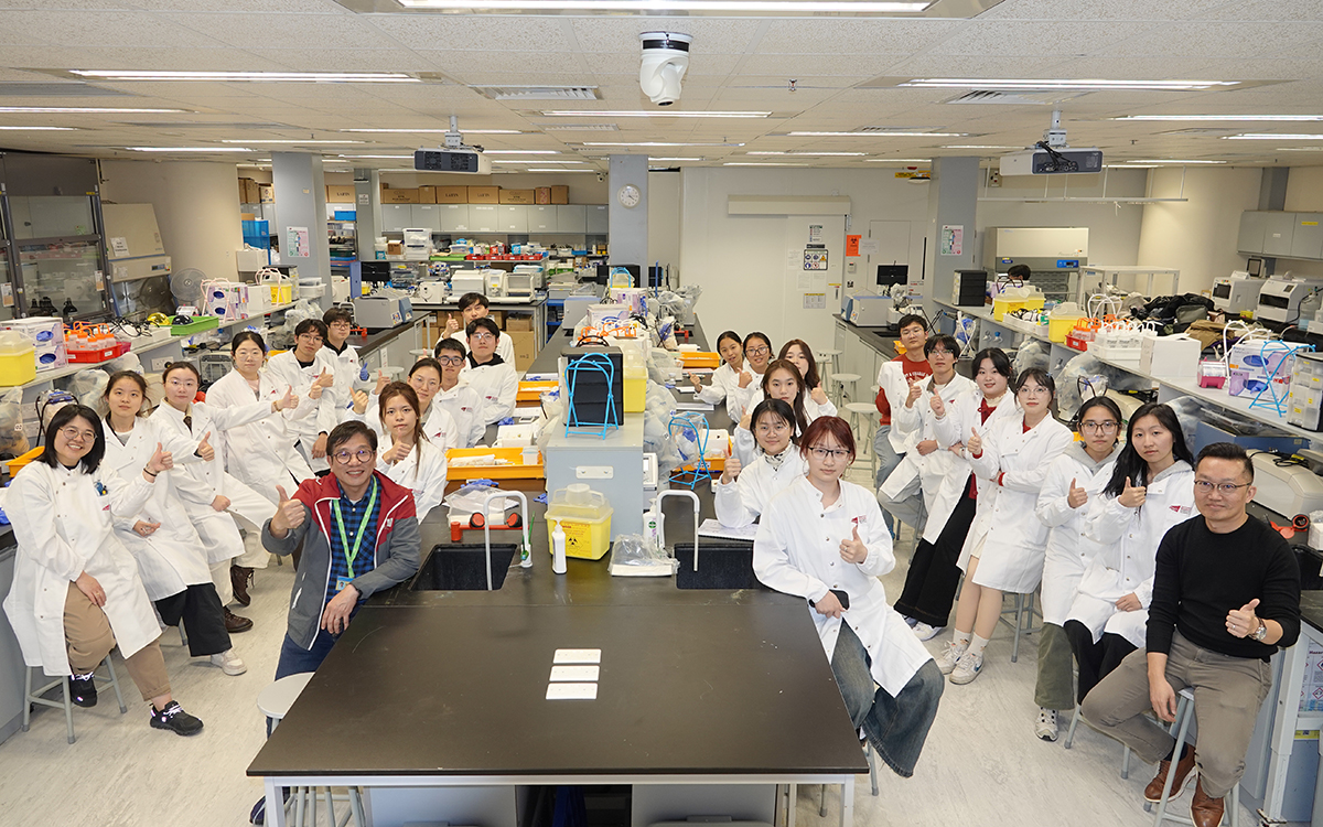 Visiting students and staff gather in the BMS laboratory following a hands-on demonstration.