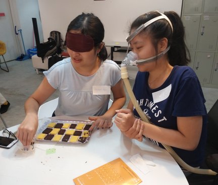 Students were paired up and their eyes were covered in turns to decorate cookies with chocolate beans to form a braille cell. The one who could see instruct the other how to put the chocolate beans onto the cookies. 同學兩人一組, 其中一人蒙着雙眼, 把巧克力豆和曲奇組成點字陣, 另一同學負責指示