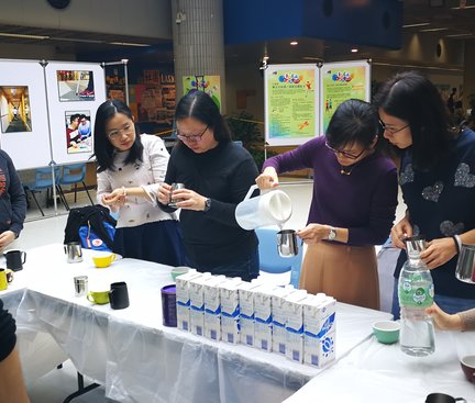 The participants were surrounding the tutors and practicing the technique of adding milk into coffee. 參加者圍着教練學習加奶入咖啡