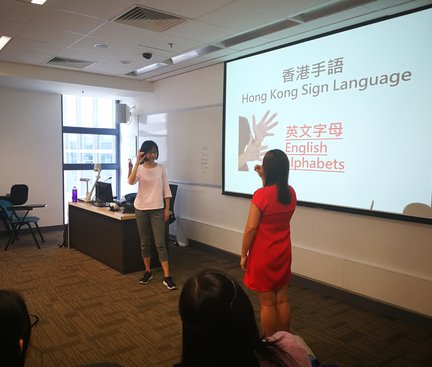 A student in red dress had been invited out to demonstrate sign language with the tutor. 穿紅裙的同學被邀請示範手語手勢
