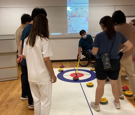 Tutor was demonstrating how to play floor curling with tools. 導師示範用工具玩地壺