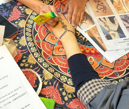 The artist was drawing Henna designs on the student's hand. 導師在學生手上繪畫Henna圖案。
