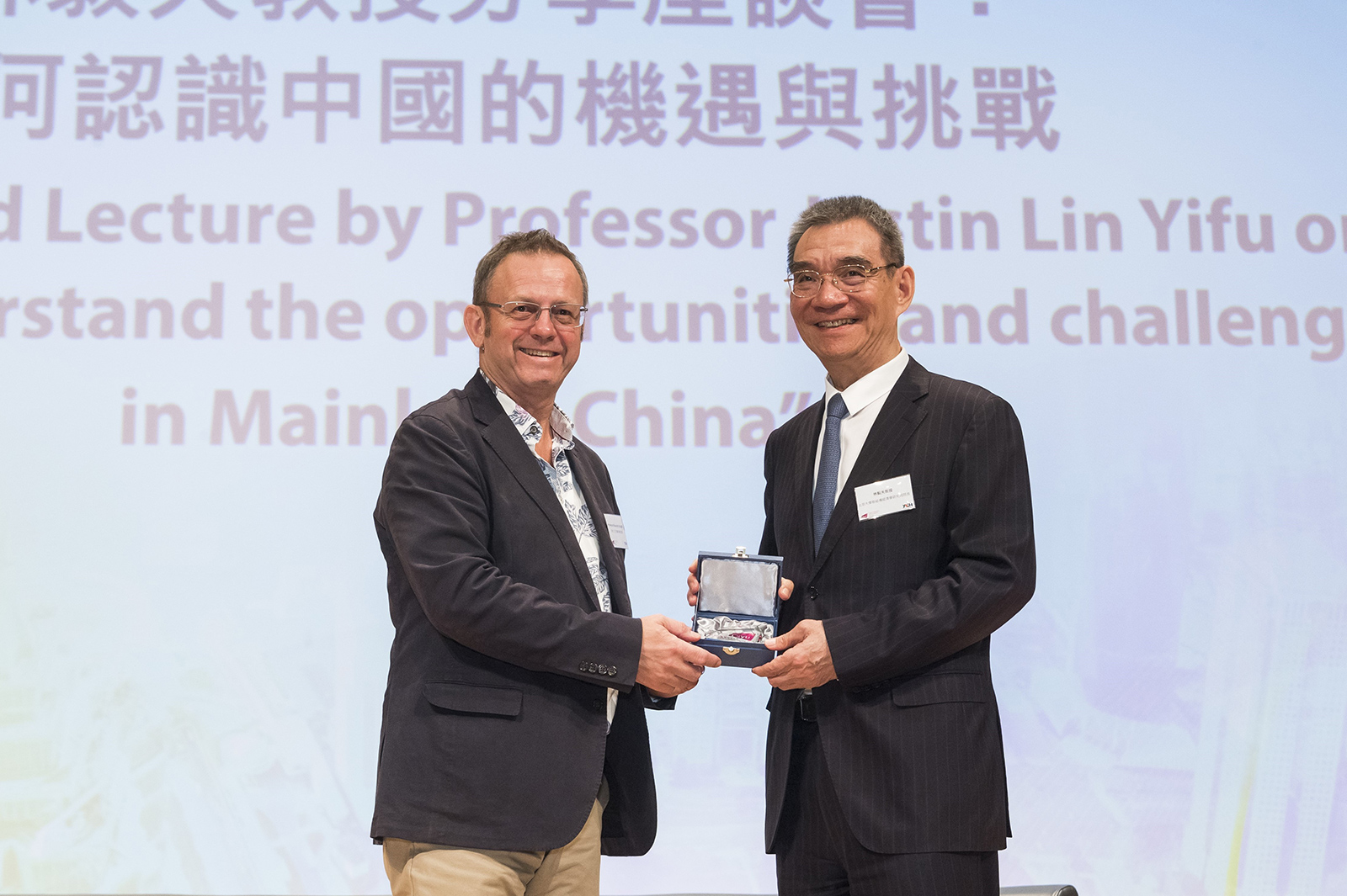 Professor Richard M. Walker (left), Dean of the College of Liberal Arts and Social Sciences, presents a commemorative gift to Professor Justin Lin Yifu (right).