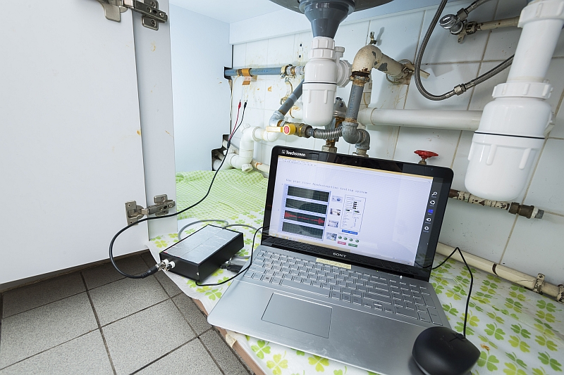 The system developed by the CityU team is shown here examining a gas pipe in the kitchen of a flat. The small box on the left is a USB-based data acquisition box.