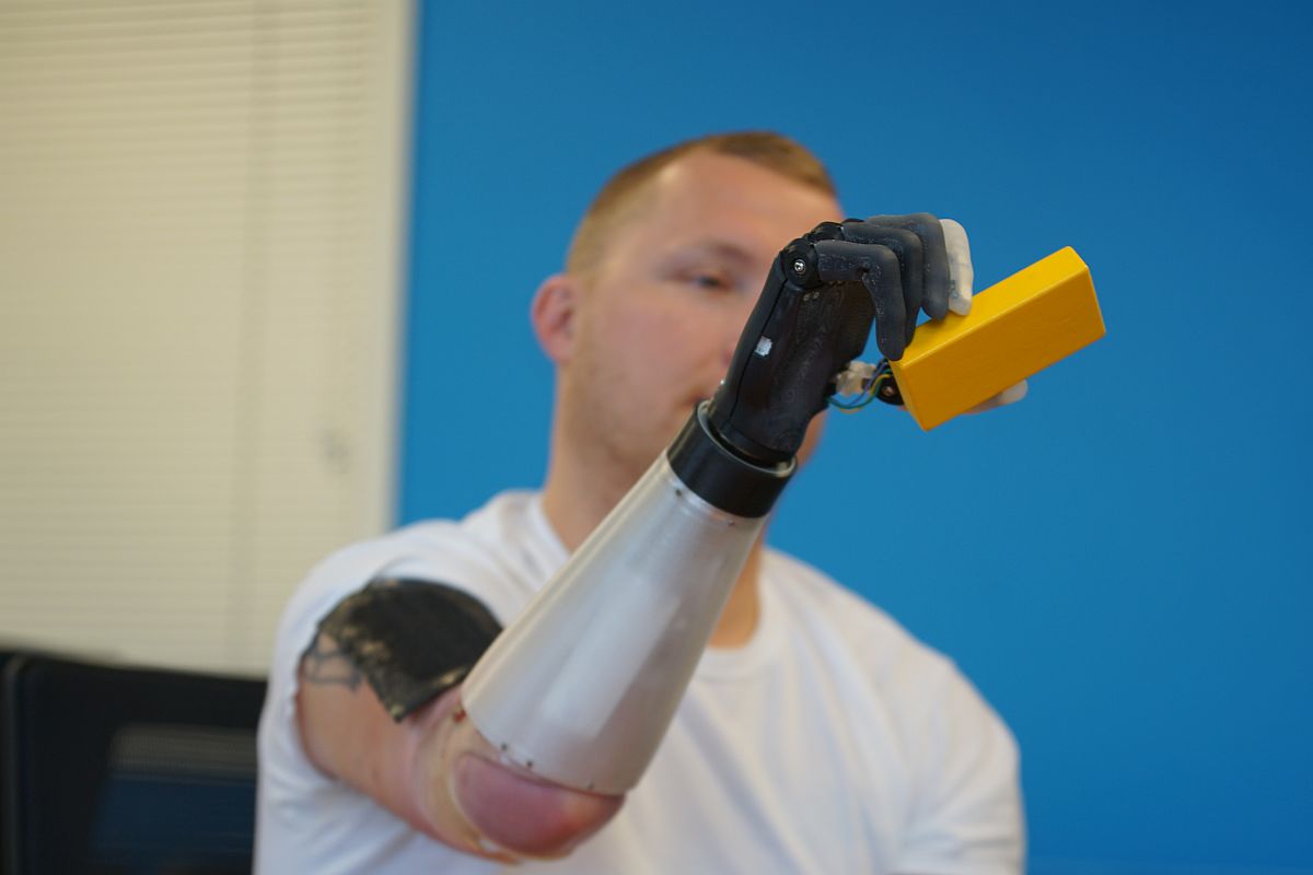 The user wears the VR device (black part) on his upper arm. The sensor on the prosthetic hand can detect the shape of the object he grasped, and then generate a simulated “touch” through the VR device, he can then perceive the shape of the object.