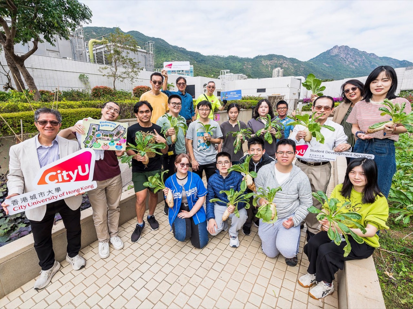 Students and staff hold up freshly harvested white radishes in the CityUHK rooftop Biodiversity Garden.