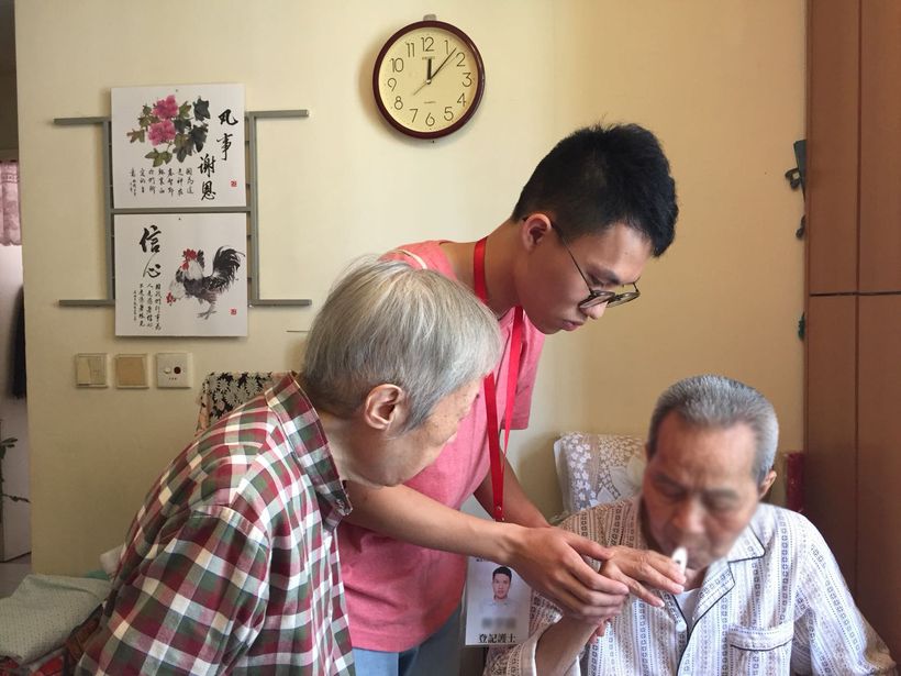 A HomAge carer checks on an elderly man during a home visit