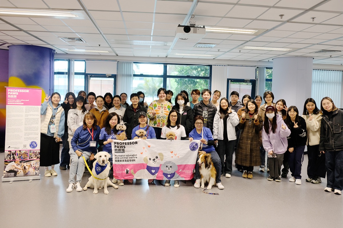 Students and handlers gathered with therapy dogs behind a Professor Paws banner at CityUHK