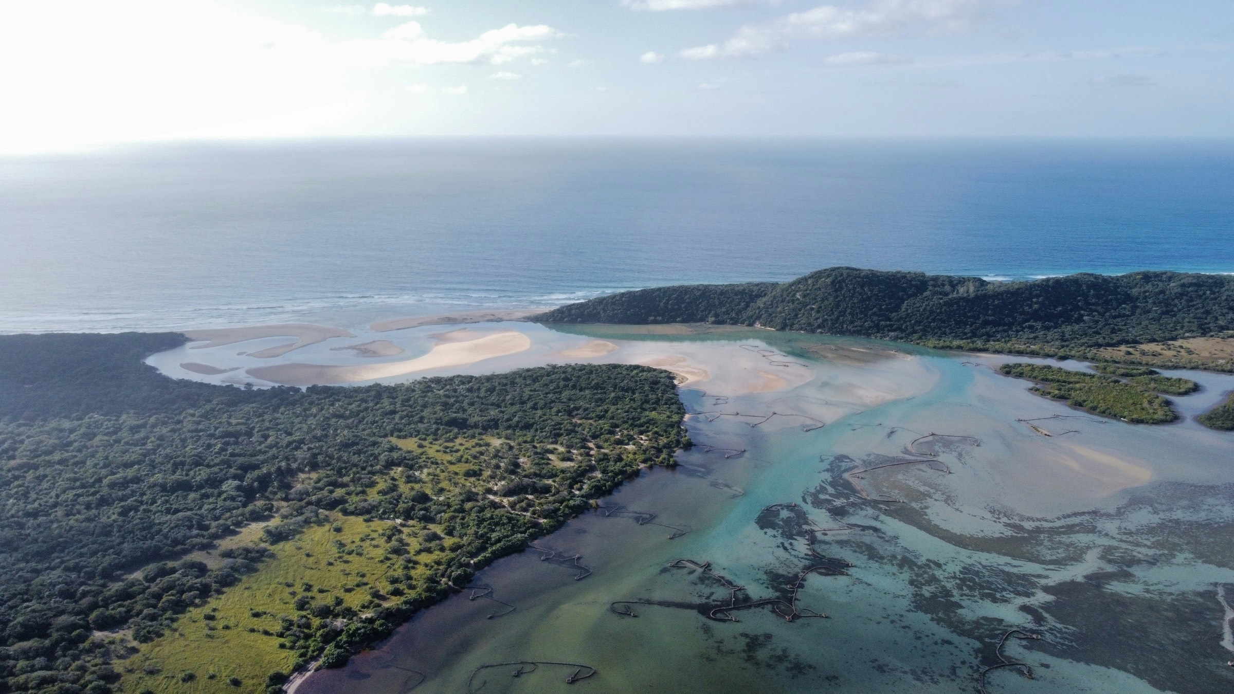 Aerial view of an estuary, where a tidal river channel and sandbanks meet the open sea