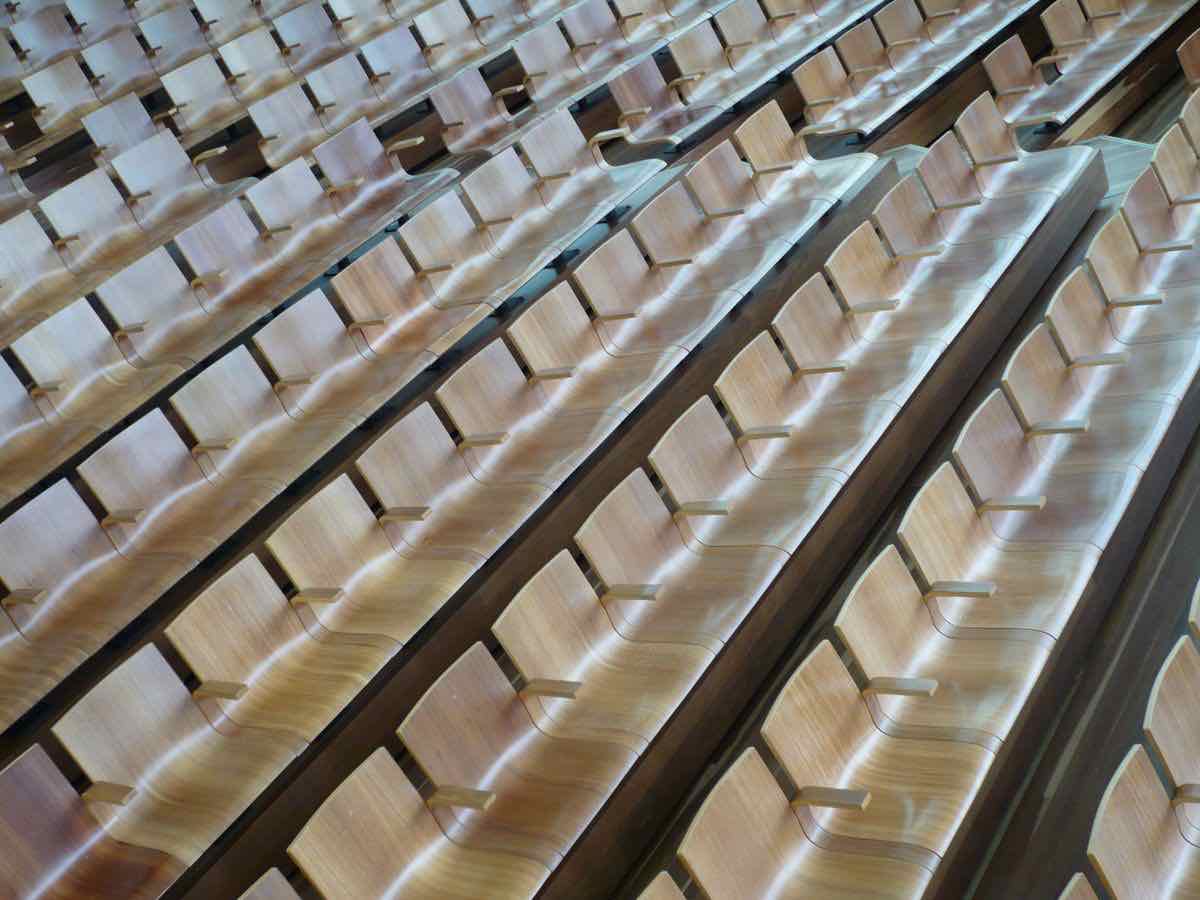 Rows of empty wooden seats in a tiered lecture theatre